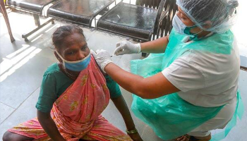 lady in saree sitting, getting vaccinated against COVID